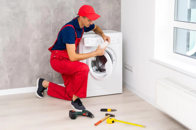 plumber overalls with tools is repairing washing machine house